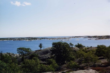 Utsikt från ön Stora Bonden, Nassa skärgård. Enar, smågranar och klippor i förgrunden, kala skär och blå himmel i bakgrunden