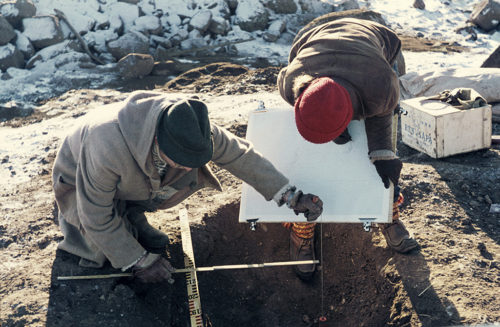 Arkeologisk undersökning av en förhistorisk grav. Två arkeologer mäter. (Obs. icke-digital dokumentation)