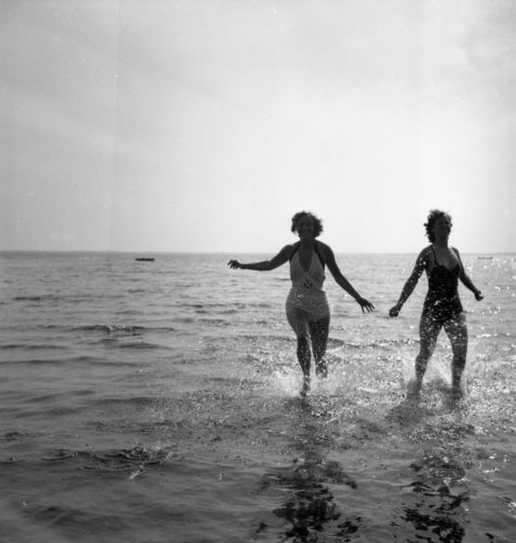 Två kvinnor springer i vattenbrynet.