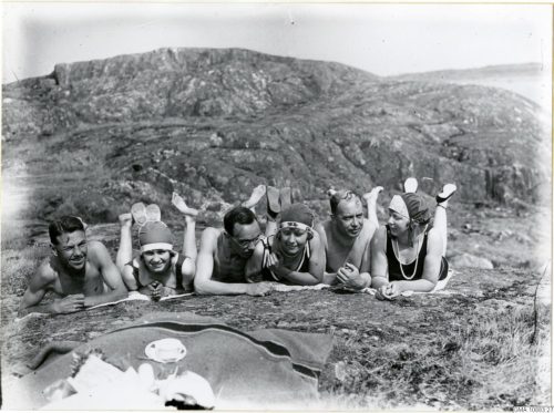 Kvinnor och män iklädda badkläder på en klippa.