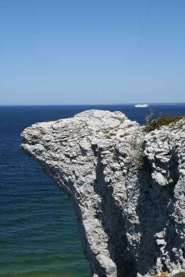 En vittrande kalkklippa som liknar ett fårhuvud mot bakgrund av blått hav med en Gotlandsfärja “i nacken“. Foto: Karin Sterner