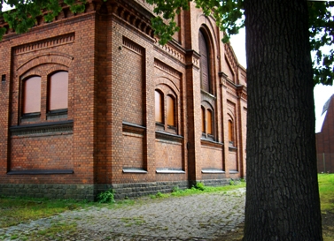 En äldre tegelbyggnad med en trädstam framför, Swartlings ridskola