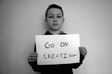 Pojke som håller en skylt med texten "Go on creating"